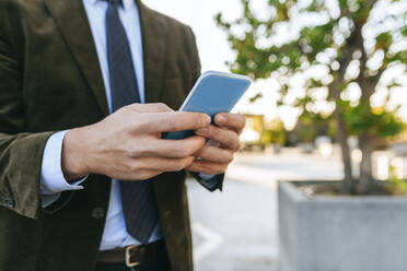 Nahaufnahme eines Geschäftsmannes, der sein Smartphone im Freien benutzt - KIJF02760