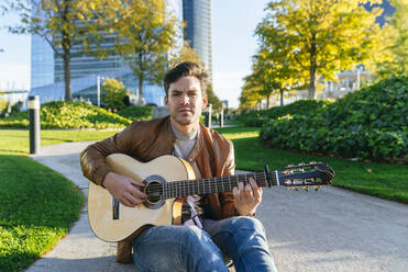 Mann spielt Gitarre in einem Stadtpark, Madrid, Spanien - KIJF02764