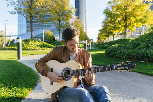 Mann spielt Gitarre in einem Stadtpark, Madrid, Spanien - KIJF02765