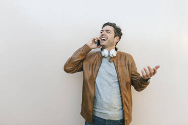 Happy man on the phone in front of a wall - KIJF02775