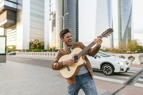 Aufgeregter Mann spielt Gitarre in der Stadt, Madrid, Spanien, lizenzfreies Stockfoto