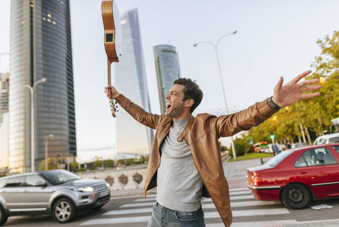 Aufgeregter Mann mit Gitarre in der Stadt, Madrid, Spanien - KIJF02792