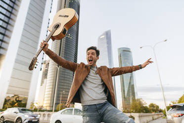 Aufgeregter Mann mit Gitarre in der Stadt, Madrid, Spanien - KIJF02793