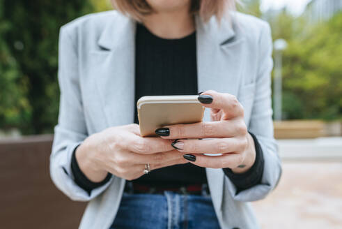 Nahaufnahme einer Frau, die im Freien ein Mobiltelefon benutzt - KIJF02796