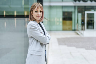 Portrait of confident busineswoman leaning against glass building - KIJF02815