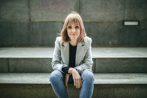 Portrait of confident woman sitting on stairs - KIJF02821