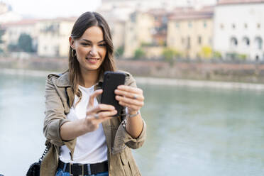 Junge brünette Frau mit Smartphone in Verona, Italien - GIOF07721