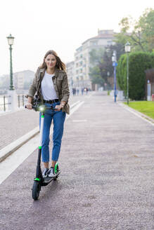 Junge Frau mit E-Scooter in Verona, Italien - GIOF07725