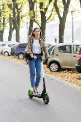 Junge Frau mit E-Scooter in Verona, Italien - GIOF07727