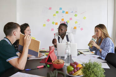 Junge Geschäftsleute beim gemeinsamen Brainstorming an einem Tisch in einem Büro - IGGF01447