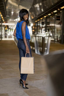 Weibliche Afroamerikanerin mit Einkaufstüten in einem Einkaufszentrum - MAUF03055