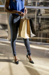 Female Afro-American with shopping bags in a mall - MAUF03056