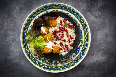 Bowl of falafel with lettuce, yogurt, pomegranate seeds, parsley, mint and Tabbouleh salad - LVF08434