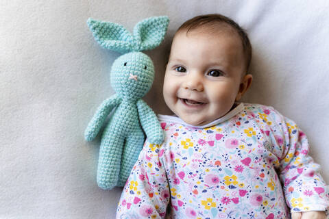 Baby girl with a bunny toy lying on bed stock photo