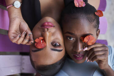 Porträt von zwei jungen Frauen, die ihre Augen mit Blumen bedecken - VEGF00785