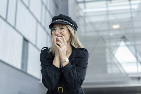 Junge blonde Geschäftsfrau mit schwarzer Seemannsmütze und lachend - ERRF02091