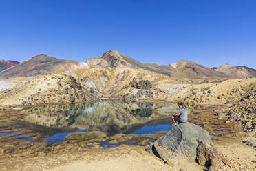 Neuseeland, Nordinsel, Männlicher Wanderer entspannt sich an den Emerald Lakes in der vulkanischen Hochebene der Nordinsel - FOF11069