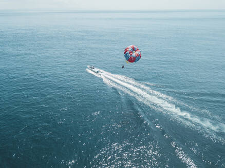 Nusa Dua, Bali, Nusa Dua, Luftaufnahme von Person Parasailing und Motorboot - KNTF03713