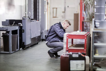 Junger Mann arbeitet in einer Druckerei - SGF02442