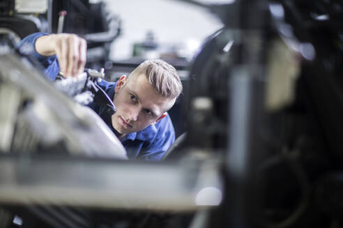 Young man adjusting a machine in a printing company - SGF02443