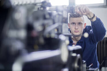 Junger Mann beim Einstellen einer Maschine in einer Druckerei - SGF02444