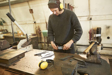 Mann fertigt Messer in einer Werkstatt - PMF00885