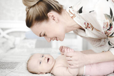 Mother with her cute smiling baby girl in the bedroom - EYAF00671