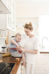 Mother with her little boy with juice in the kitchen - EYAF00679