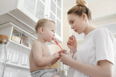 Mutter mit ihrem kleinen Jungen, der ein Glas Saft trinkt - EYAF00680