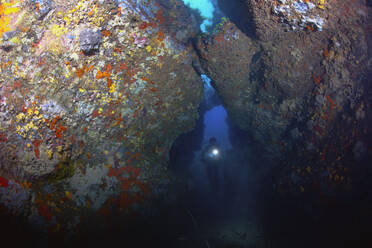 France, Corsica, Scuba diver swimming between rocks - ZCF00839