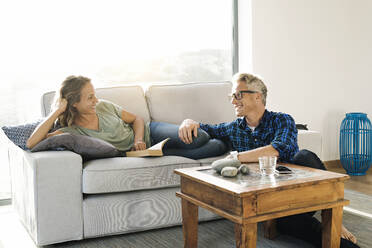 Paar lächelt sich gegenseitig auf der Couch in einem modernen Haus an - SBOF02061