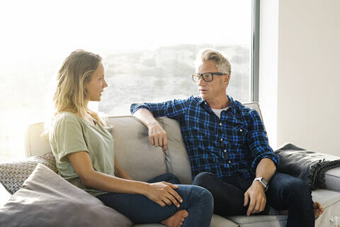 Pärchen im Gespräch auf der Couch in einem modernen Haus, lizenzfreies Stockfoto