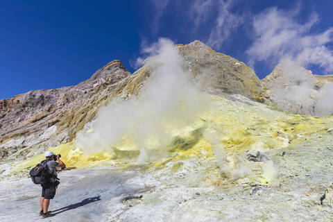 Neuseeland, Nordinsel, Whakatane, Männlicher Wanderer fotografiert aktive Fumarole auf White Island (Whakaari), lizenzfreies Stockfoto