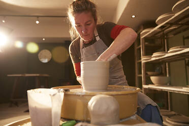 Woman working with a pottery wheel in her workshop - PMF00911