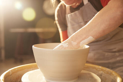 Female potter in her workshop at a shelf - PMF00912