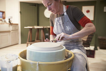 Woman working with a pottery wheel in her workshop - PMF00913