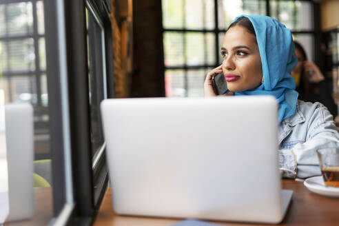 Geschäftsfrau mit türkisfarbenem Hijab in einem Café und bei der Arbeit - ERRF02124