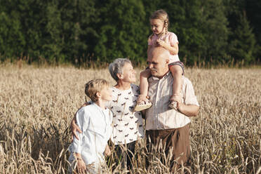 Family portrait of grandparents with their grandchildren in an oat field - EYAF00700