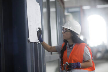 Storekeeper female in a warehouse looking to a plan - CAVF69387