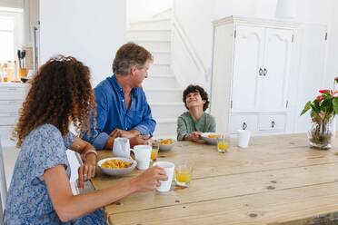 Eltern beobachten ihren Sohn beim Frühstück zu Hause beim Lächeln - ISF22722