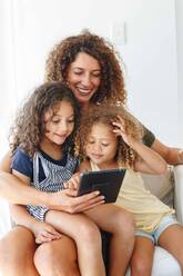 Mother and daughters using digital tablet at home - ISF22733