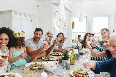 Familie stößt mit Wein am Esstisch in der Wohnung an - ISF22759