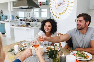 Family toasting wine at dining table in home party - ISF22760