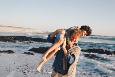Vater trägt Sohn über die Schulter am Strand - ISF22771