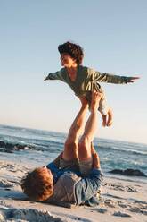 Vater hebt Sohn in der Luft mit Beinen am Strand - ISF22781