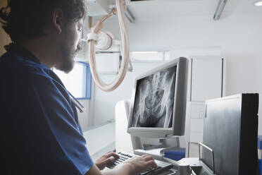 Junger männlicher Röntgenassistent beim Betrachten einer Röntgenaufnahme des Beckens in der radiologischen Abteilung - ISF22788