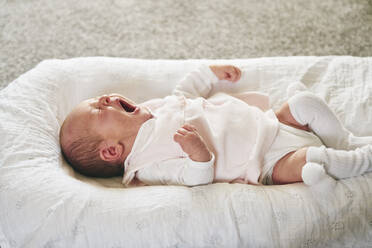 Baby gähnt auf einem U-förmigen Kissen zu Hause - CUF53234