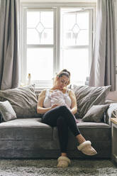 Mutter mit Baby an der Brust auf dem Sofa - CUF53239