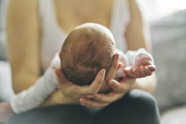 Mutter stützt Kopf des Babys auf dem Schoß - CUF53241