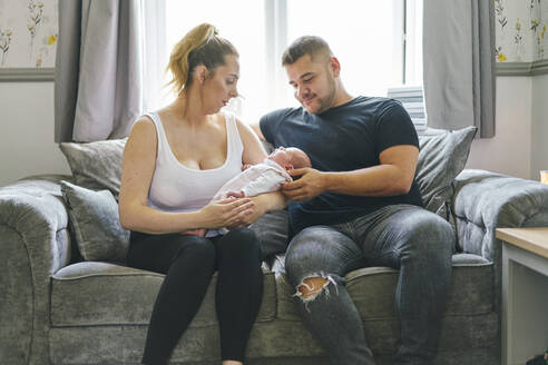 Ehepaar wiegt Baby auf Sofa - CUF53242